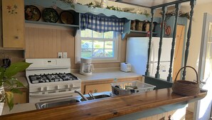 Cozinha com fogão a gás, máquina de café e janela.