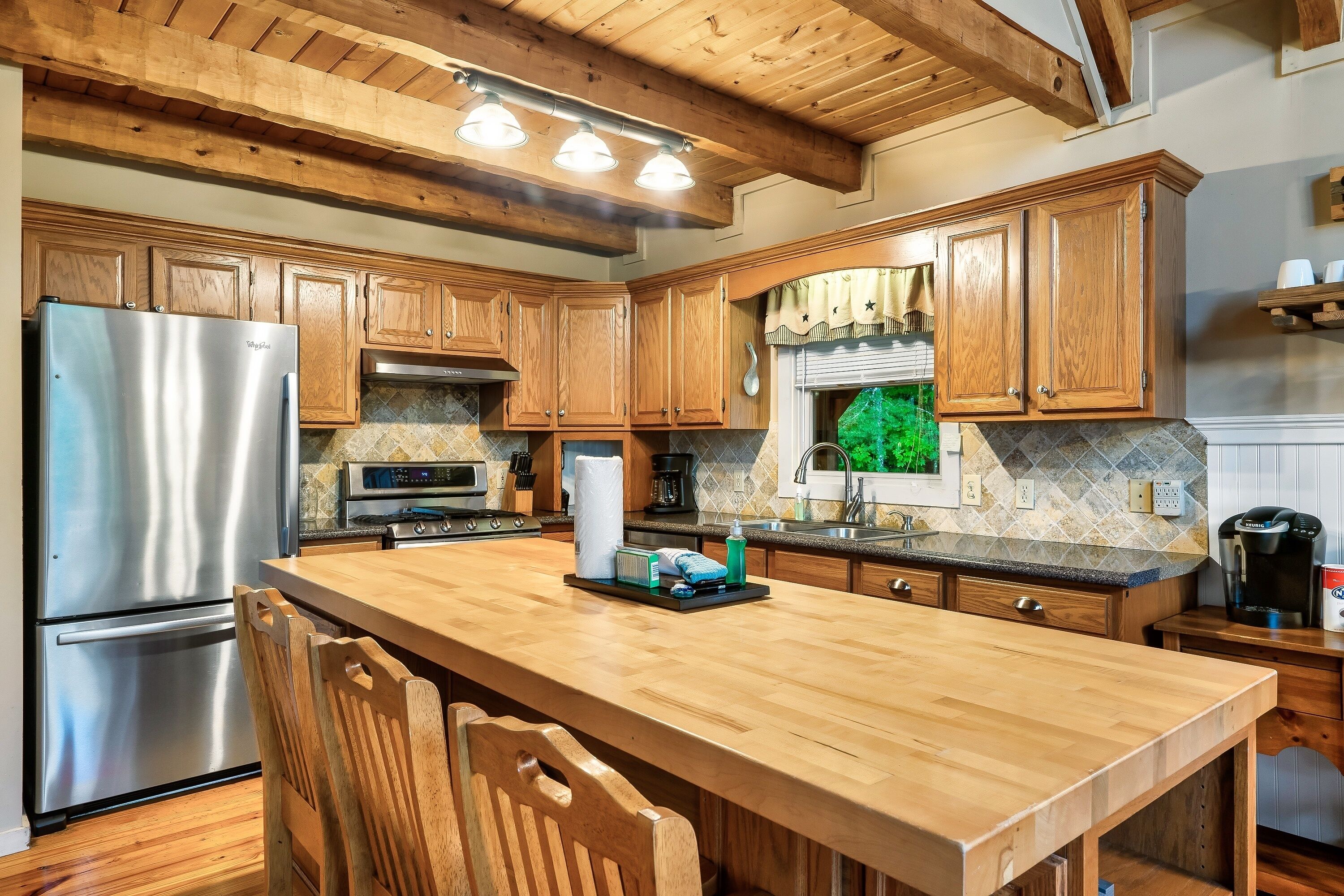 Una cocina con armarios de madera, un refrigerador de acero inoxidable, un microondas y una cafetera.