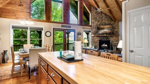 A spacious kitchen with a large island, wooden ceiling beams, and a stone fireplace. - Beautiful Views of the Smoky Mountains! Hot Tub-Game Room-3 King Beds-Sleeps 11 (Sevierville)