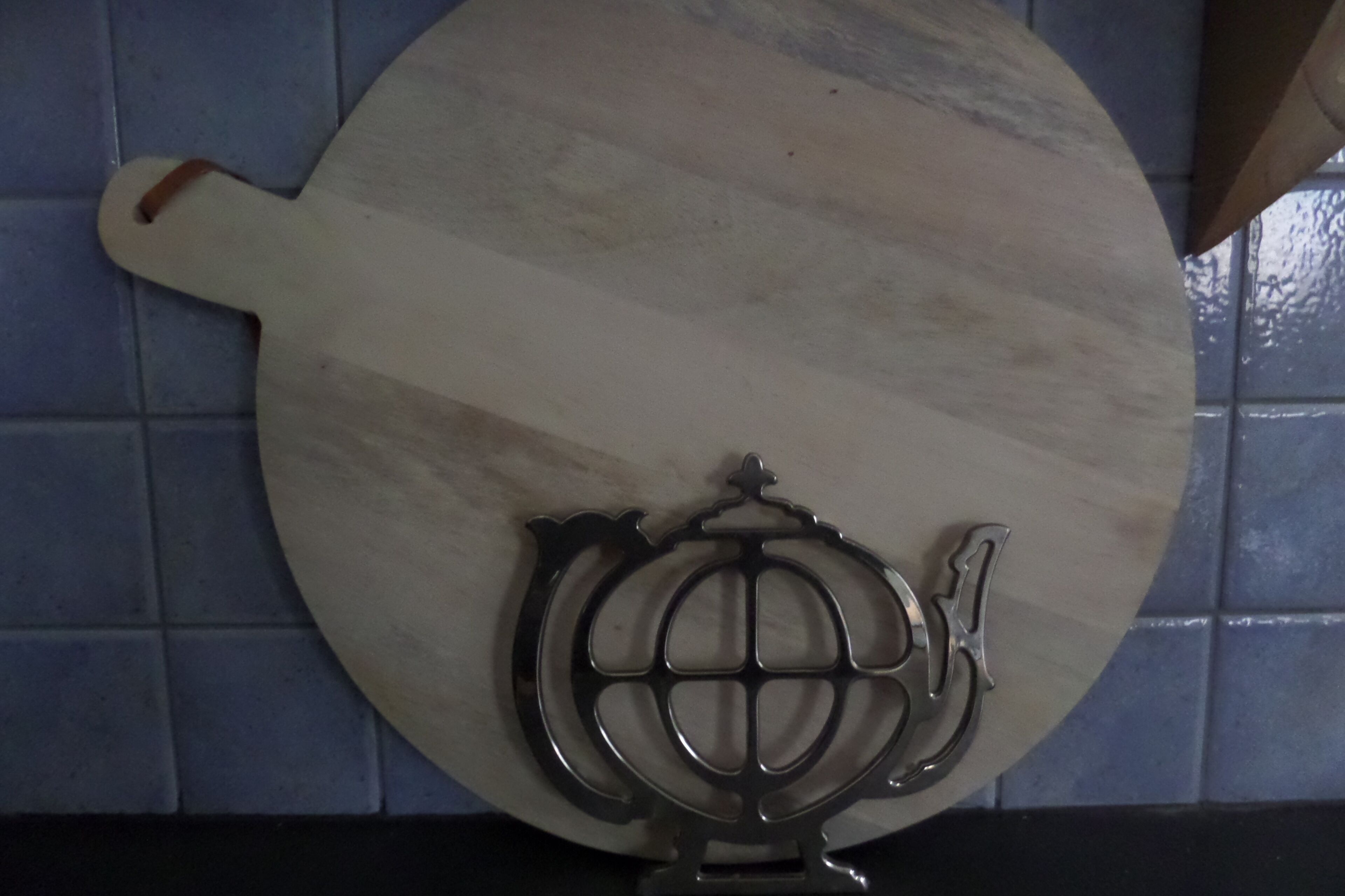 A kitchen with a wooden cutting board and a metal kitchen tool.