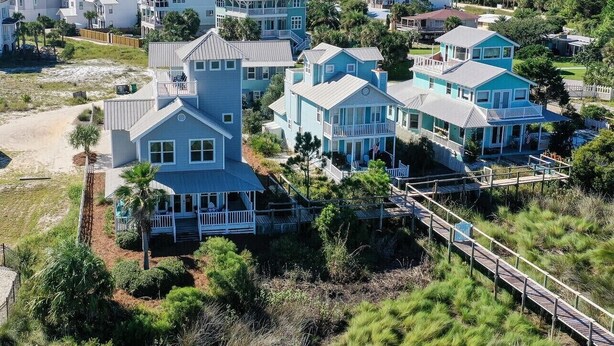 A coastal residential area with multiple two-story houses featuring balconies and a wooden deck. - Just Peachy - 4 BR/3BA Private Pool (Santa Rosa Beach)