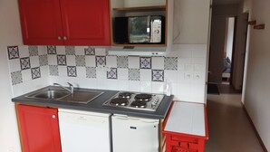 Eine kompakte Küche mit roten Schränken, einer Mikrowelle, einem Spülbecken und einem Geschirrspüler.