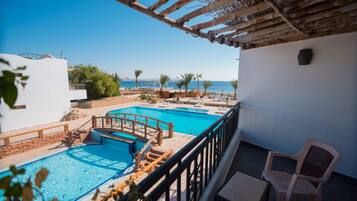 A rooftop pool area with a wooden bridge, lounge chairs, and a view of the sea.