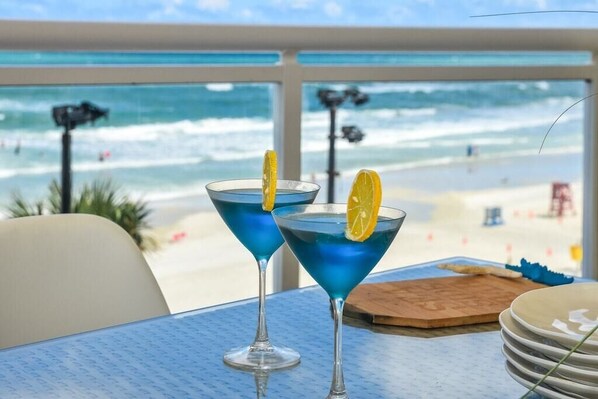Dos cócteles azules sobre una mesa, con vista a la playa y al océano.