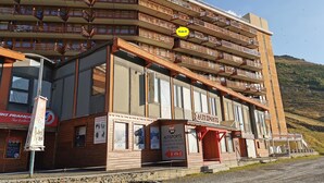 A multi-story building with balconies, a ski rental sign, and a ski resort name.
