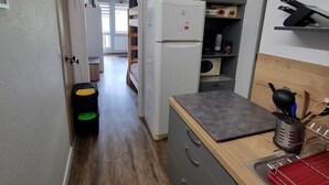 A compact kitchen with a microwave, refrigerator, and wooden countertop.