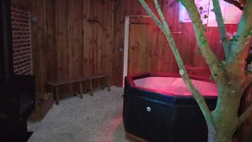 Une pièce en bois avec un jacuzzi, des bancs et un arbre.