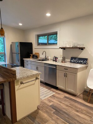 A modern kitchen with a built-in dishwasher, a stainless steel refrigerator, and a window above the sink. - Lake Samish Cabin Loft (Bellingham)