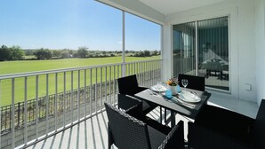 A balcony with a table set for two, overlooking a green field. - LUXURY RESORT & GOLF CONDO MIN CLOSE TO DISNEY (Four Corners)