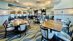 A spacious hotel dining area with multiple tables and chairs, a bar, and overhead lighting. - LUXURY RESORT & GOLF CONDO MIN CLOSE TO DISNEY (Four Corners)
