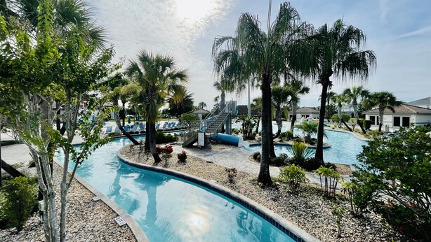 A pool area with palm trees, a water slide, and a clear sky. - LUXURY RESORT & GOLF CONDO MIN CLOSE TO DISNEY (Four Corners)