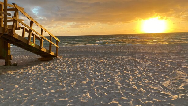 A wooden staircase leading down to a sandy beach with the ocean in the background and a sunset. - 2 Bedroom 2 Bath Beach 1 min Walk 8 People Keyless Free Parking Flex Check in (Sunny Isles Beach)