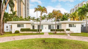 A modern hotel with a symmetrical facade, palm trees, and a paved walkway leading to the entrance. - 2 Bedroom 2 Bath Beach 1 min Walk 8 People Keyless Free Parking Flex Check in (Sunny Isles Beach)