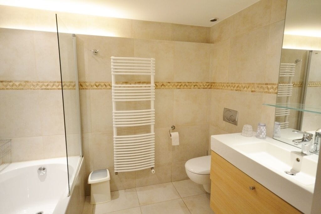 A bathroom with a bathtub, toilet, and vanity with a mirror.