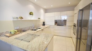 Una cucina moderna con mobili bianchi, un piano di lavoro in granito e un frigorifero in acciaio inossidabile.