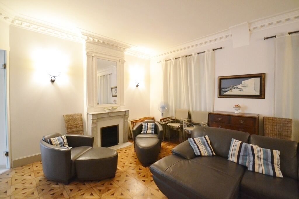 A living room with a fireplace, leather sofas, a dining table, and a painting on the wall.