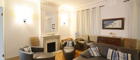 A living room with a fireplace, leather sofas, a dining table, and a painting on the wall.