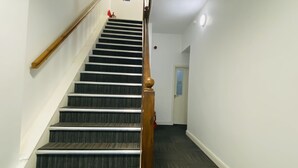 Eine Treppe mit hölzernen Geländern und Teppichstufen, die zu einer Tür führt.