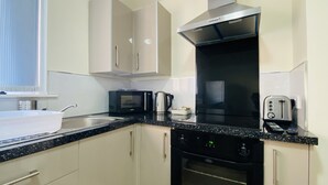 Eine moderne Küche mit einem schwarzen Herd, einer Mikrowelle, einem Wasserkocher und einem Toaster.