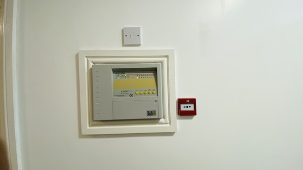 A control panel with a digital display and buttons, mounted on a white wall.