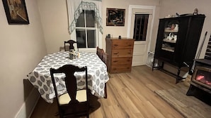 A dining area with a table set for two, a wooden dresser, and a cabinet with dishes. - Charming Farmhouse on a working farm. (Pittsfield)