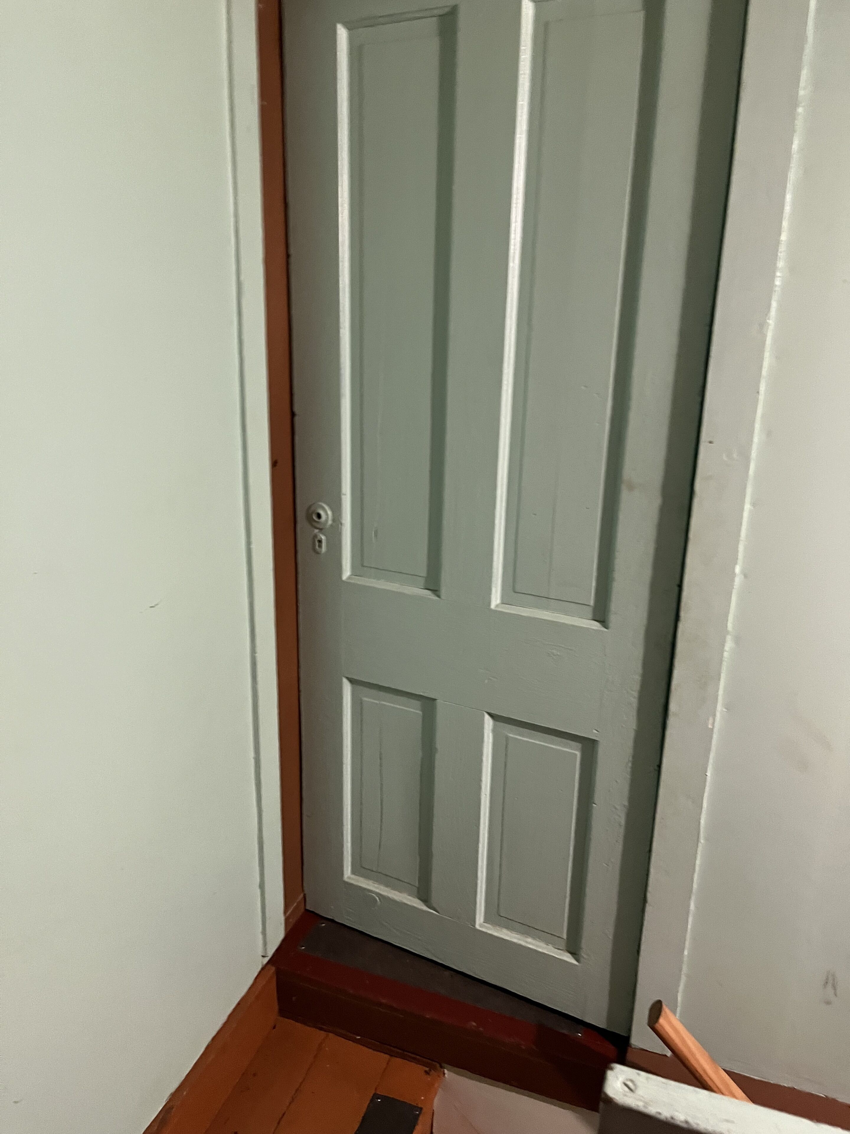 Una puerta cerrada con un ojo de cerradura y un pequeño escalón que lleva a ella.