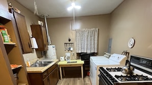 A compact kitchen with wooden flooring, a gas stove, a refrigerator, and a coffee maker. - Charming Farmhouse on a working farm. (Pittsfield)