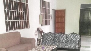 A living room with two sofas, a patterned rug, and a tiled floor.
