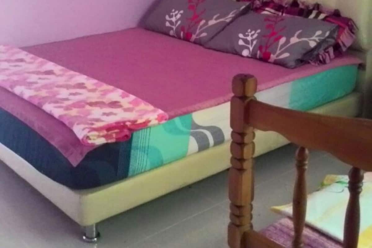 A bed with a floral bedspread, a headboard, and multiple pillows.