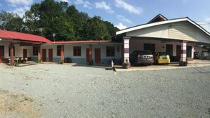 A two-story building with a red roof and a covered area with a yellow vehicle parked inside.