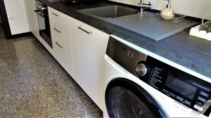 A compact kitchen with a built-in washer and dryer, a microwave, and a sink with a faucet. - Bra Luxury Rooms & Apartment (Verona)