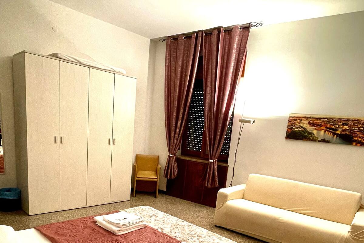Een hotelkamer met een bed, een slaapbank, een kledingkast en een raam met gordijnen.