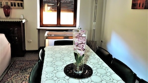 A dining area with a table set for two, a vase with flowers, a window with blinds, and a painting on the wall. - Bra Luxury Rooms & Apartment (Verona)