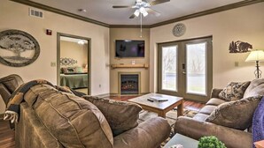 A living room with a fireplace, leather couches, a ceiling fan, and a television. - Close To It ALL with Indoor & Outdoor Pools (Pigeon Forge)