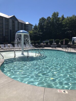 A swimming pool with a fountain, lounge chairs, and a no-diving sign.