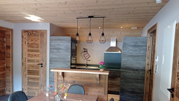 Una cocina moderna con una isla central, armarios de madera e iluminación colgante.