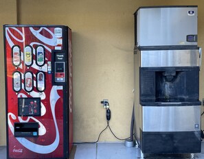 A Coca-Cola branded beverage vending machine next to a stainless steel water dispenser. - Westen Motel (Scooba)