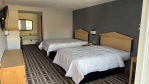 A hotel room with two beds, a wooden dresser, a mirror, and a bathroom with a towel rack. - Westen Motel (Scooba)