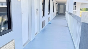 A corridor with doors, a railing, and a covered walkway. - Westen Motel (Scooba)