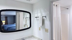 A bathroom with a large mirror, a shower curtain, and a towel rack. - Westen Motel (Scooba)