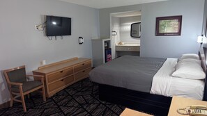 A hotel room with a bed, a desk, a chair, a television, a mirror, a telephone, and a framed picture on the wall. - Westen Motel (Scooba)