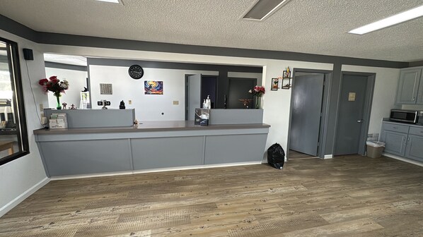 A modern kitchen with grey cabinetry, a wooden floor, a built-in island with a sink, and a microwave above the cabinets.