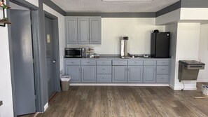 A compact kitchen with grey cabinets, a microwave, a coffee maker, and a refrigerator. - Westen Motel (Scooba)
