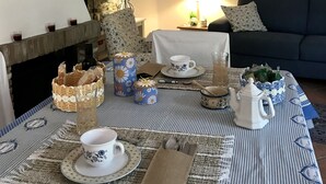 Un soggiorno accogliente con camino, un tavolo da pranzo apparecchiato per il tè e un divano scuro.