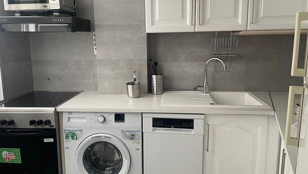 Une cuisine compacte équipée d’un four à micro-ondes, d’une cuisinière, d’un évier et d’un lave-linge.