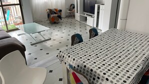 Un salon moderne avec une table basse en verre, un canapé, une nappe à pois et un téléviseur posé sur un meuble.