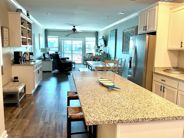 A modern kitchen with a granite countertop, stainless steel appliances, and a dining area with a view.