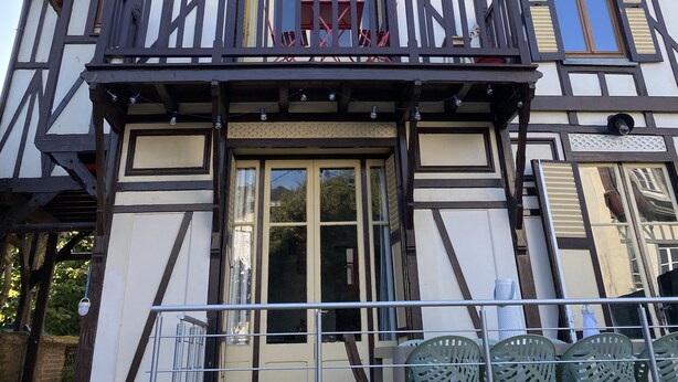 A multi-story building with a traditional architectural style, featuring a balcony with railings and a decorative cornice.