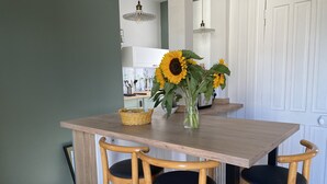 A kitchen with a wooden table, three chairs, and a vase with sunflowers.