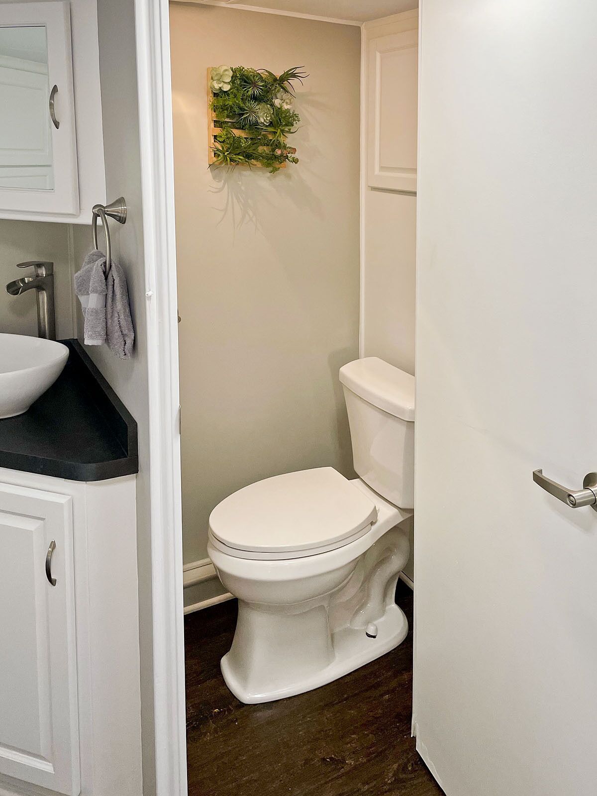 Une salle de bain avec des toilettes blanches, un lavabo doté d’un plan-vasque noir et un porte-serviettes.